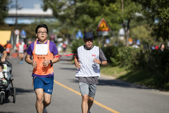 지난 12일 서울 여의도 한강시민공원에서 열린 시각장애인 마라톤에서 OCI 직원이 마라토너의 도우미로 함께 뛰고 있다. OCI는 지난 8일 창립 60주년을 기념해 60일 동안 전 임직원이 장애인을 돕는 릴레이 봉사활동을 하고 있다.   OCI 제공